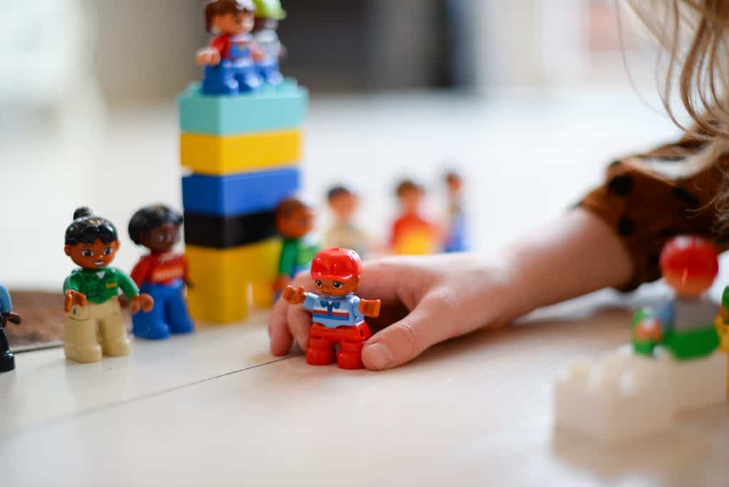 Child hand playing with duplos on the floor.