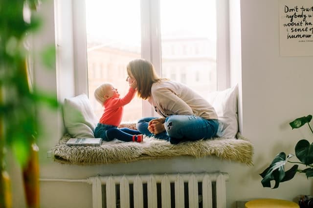 Mom and daughter smiling and sitting on window seat