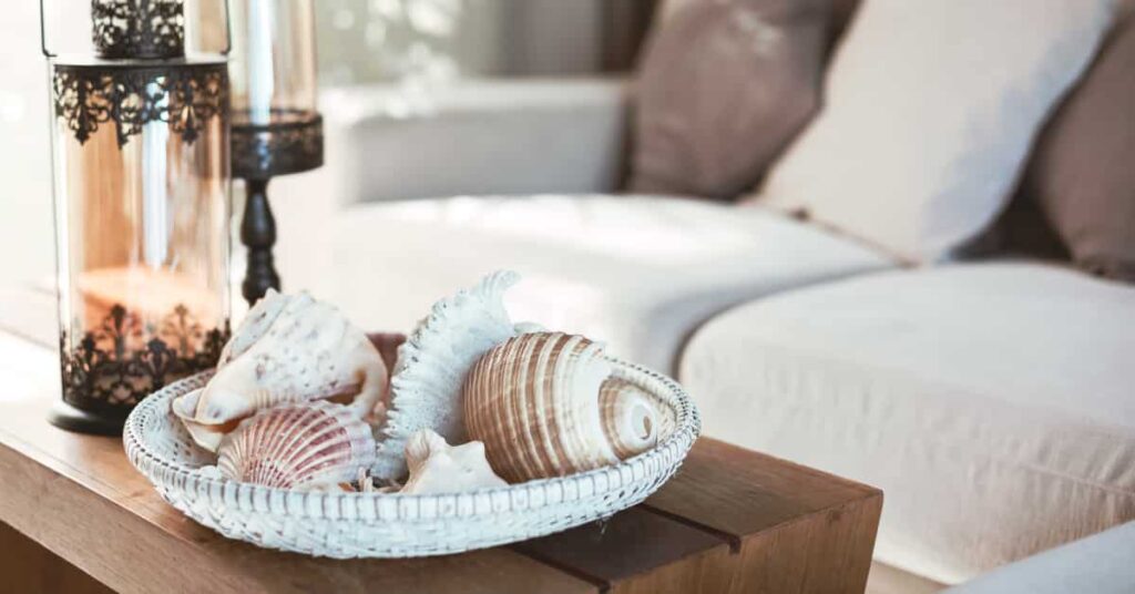 Summer decorations in a living room, including a coffee table with candles and a basket of seashells.