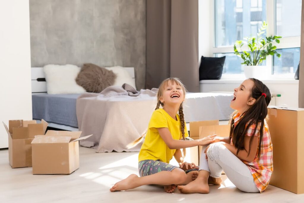 Two girls laughing in a room with boxes where they are decluttering