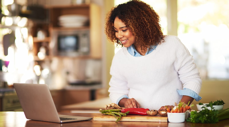 Woman cooking looking at a recipe on a computer screen.