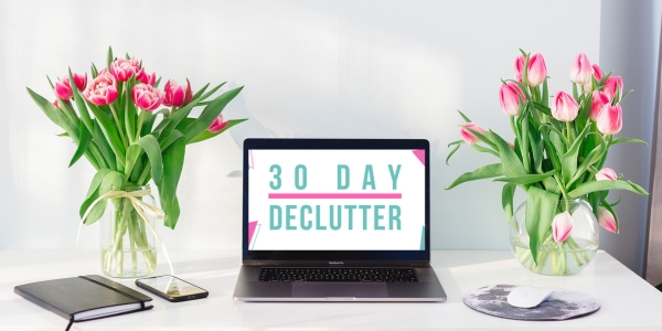 Laptop sitting on a desk with the 30 Day Declutter logo on it. Two vases with pink tulips on each side of the laptop.