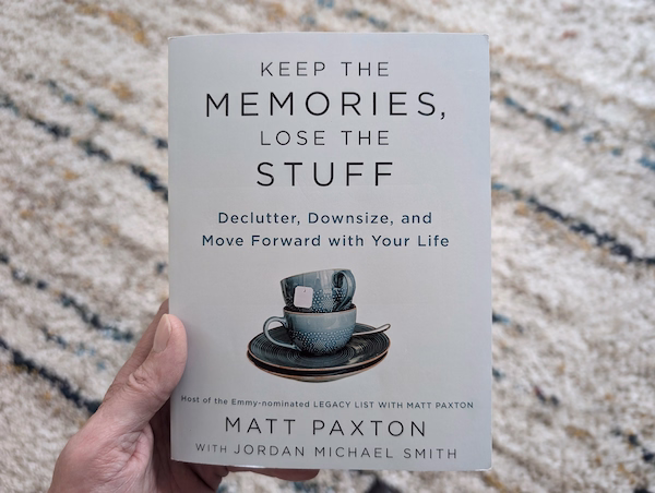 Part of a hand holding the book,"Keep the Memories, Lose the Stuff."