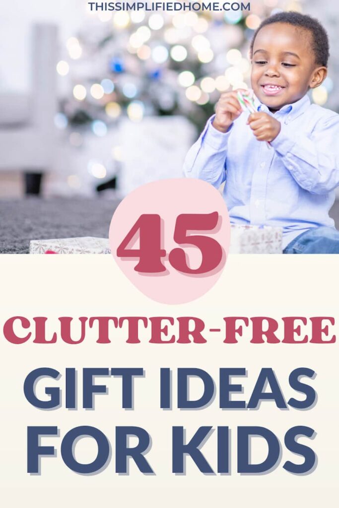 Little boy sitting in front of a Christmas tree and opening a candy cane. This is a Pinterest image with the title 45 Clutter-Free Gift Ideas for Kids.